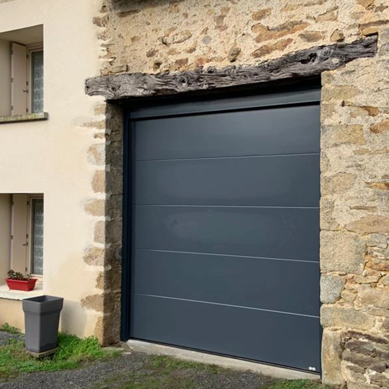 Porte de garage anthracite posée sur une maison en pierre