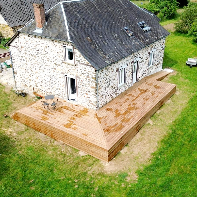 Vue aérienne d'une terrasse en bois autour d'une maison en pierre